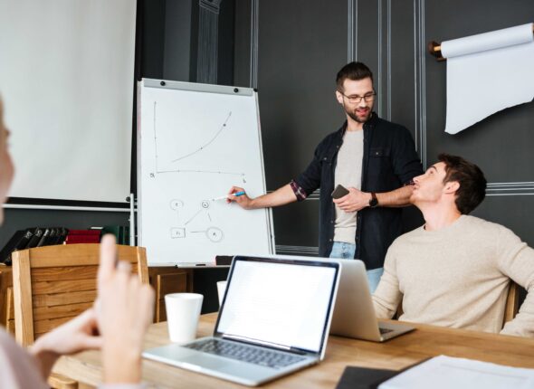 three-young-colleagues-sitting-while-work-with-laptops-desk (1)